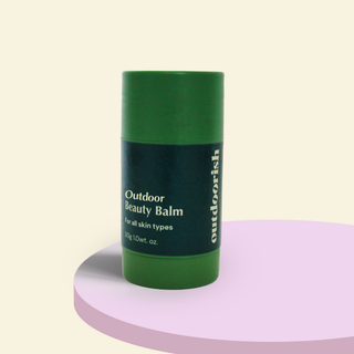 Outdoorish Outdoor Beauty Balm stick on a pastel stand